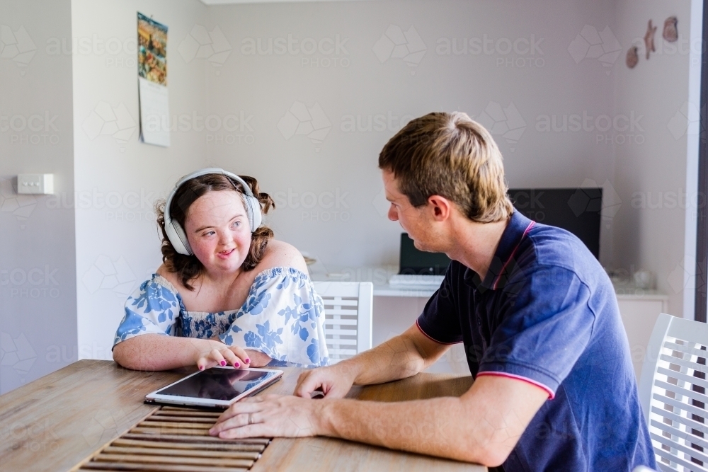 Happy teen wearing headphones talking at table with ot ndis worker austockphoto 000205870