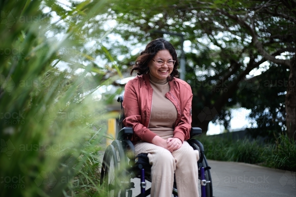 Smiling woman with disability sitting in a wheelchair outside next to a tall grass austockphoto 000188553